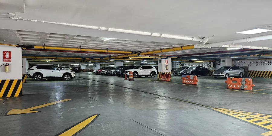 Nivel del estacionamiento del hotel, techado e iluminado, con coches estacionados y las guías pintadas en amarillo