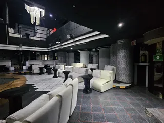 Sala de Ópera 29 con sillones blancos, mesas altas y el barandal del entrepiso
