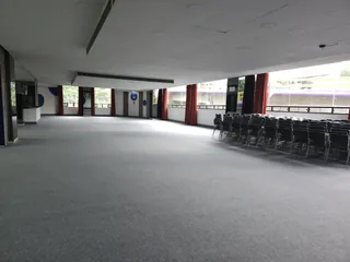 Salón vacío con un muro de ventanas al exterior y las sillas apiladas a un costado