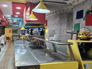 Barra caliente del buffet, en acero, con las torres de platos y un frutero al costado