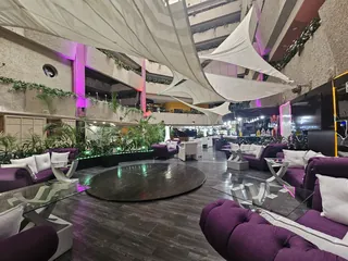 Mesa baja redonda rodeada de sofás, con las columnas iluminadas al fondo