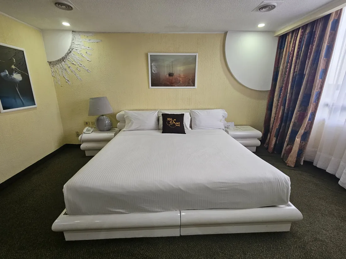 Suite Imperial: cama vestida en blanco, cortinas y alfombra verde